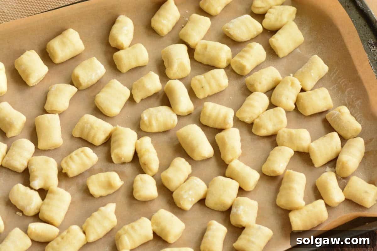 Pillowy Homemade Gnocchi Perfection 9 Rolled gnocchi pieces laid out on a parchment-lined sheet, ready for flash freezing.