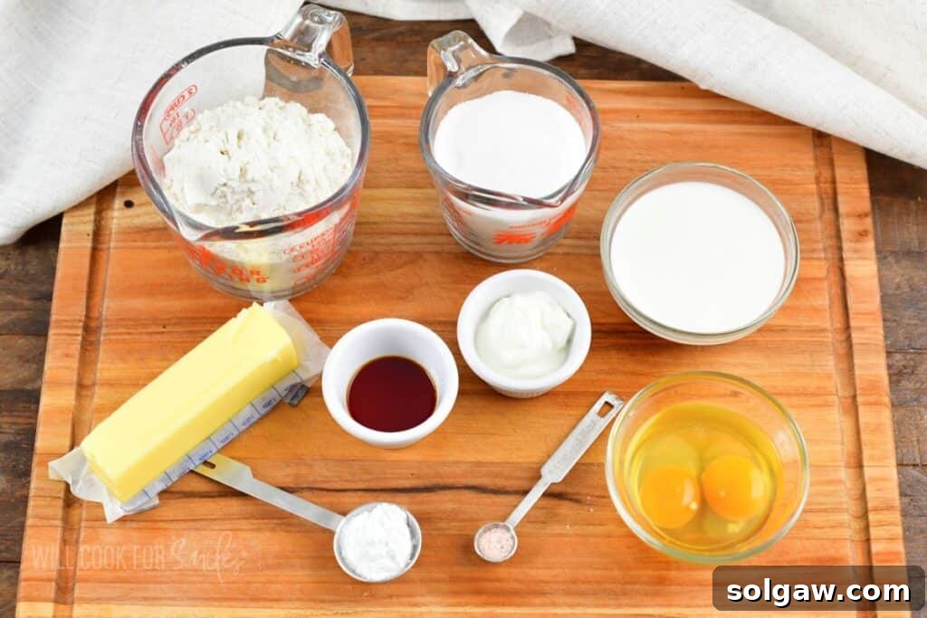 Arrangement of ingredients for Irish tea cake on a wooden cutting board, including butter, sugar, eggs, flour, and milk.