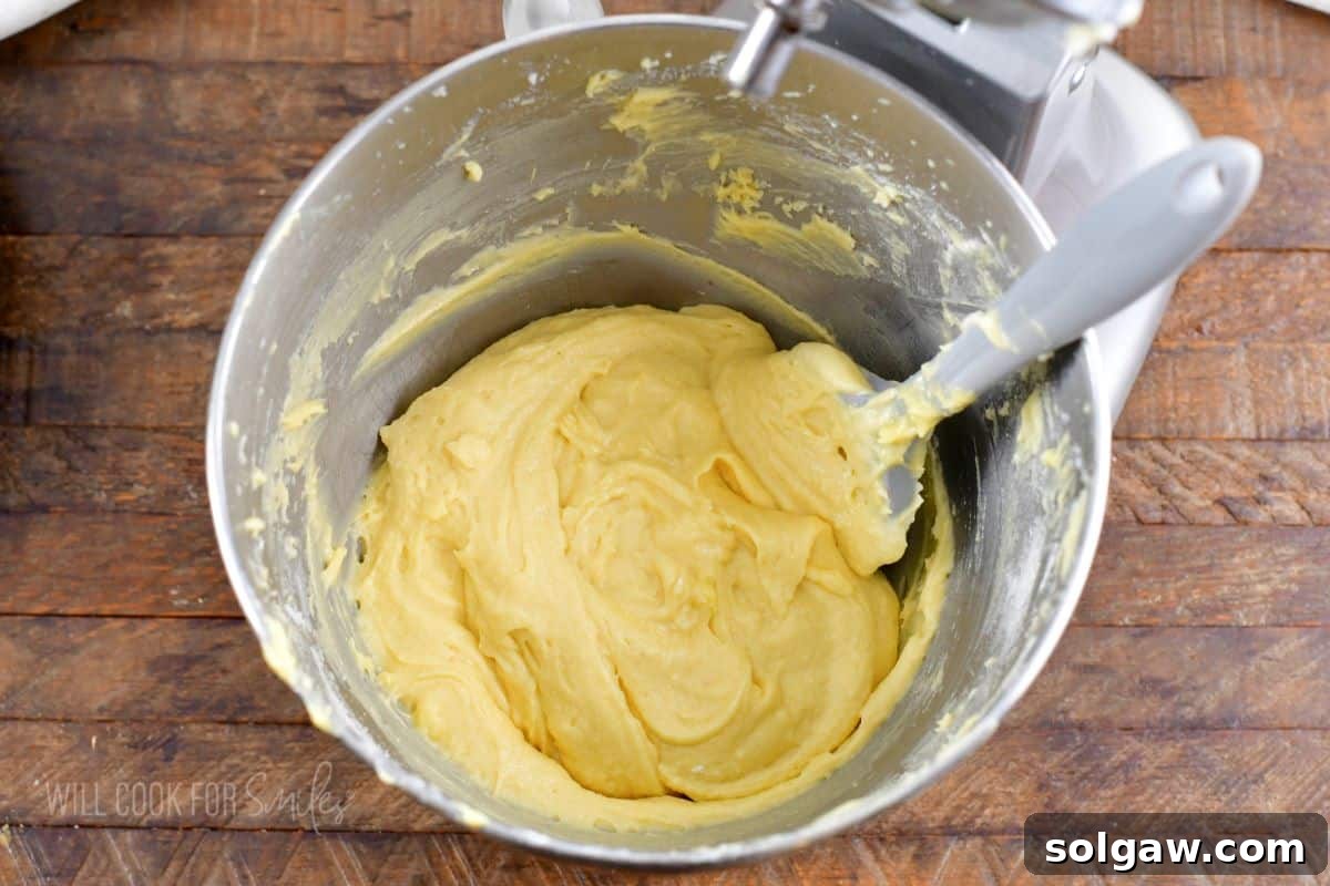 Yellowish cake batter in a mixing bowl with a spatula, showing a smooth, creamy texture.