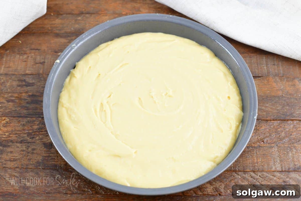 Smooth cake batter evenly spread in a round cake pan, ready for baking.
