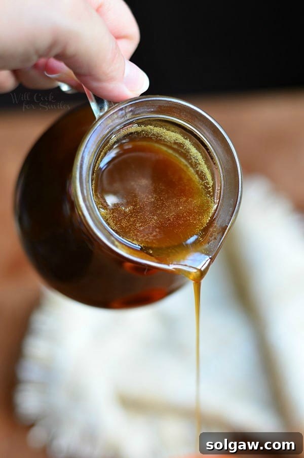 Close-up shot of fluffy pancakes topped with generous amounts of Homemade Pumpkin Syrup, inviting you to savor fall flavors.
