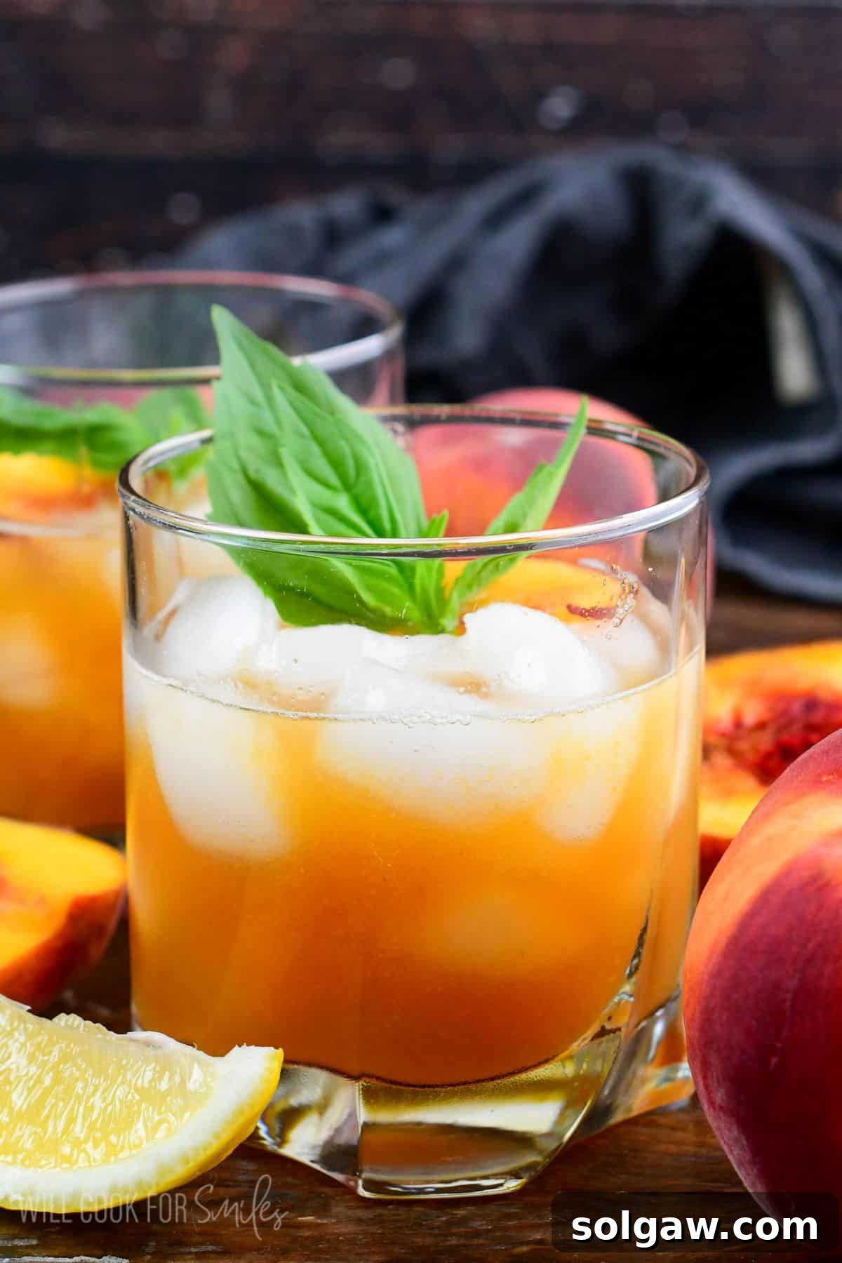 Peach bourbon smash in a glass with mint and peaches on top as garnish.