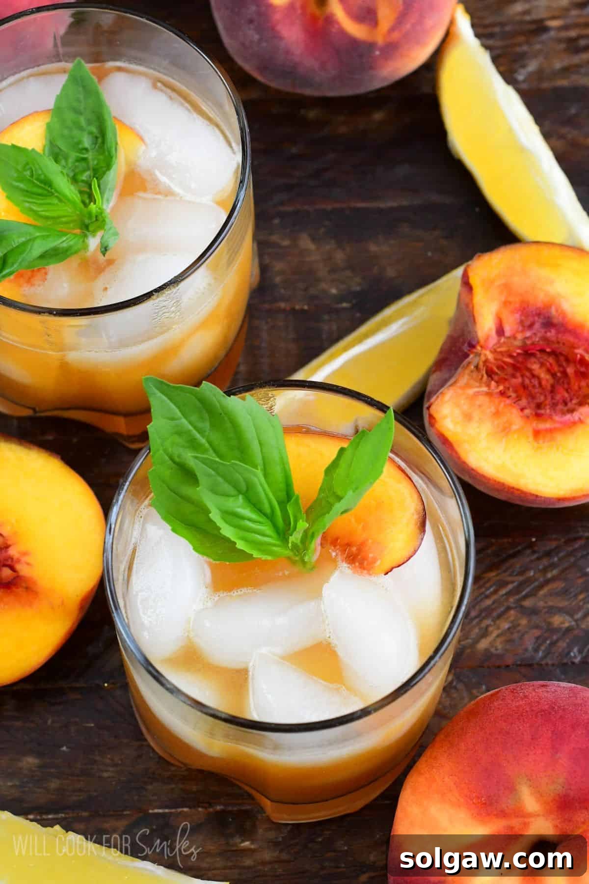Peach smash bourbon in a glass with peaches and mint as garnish.