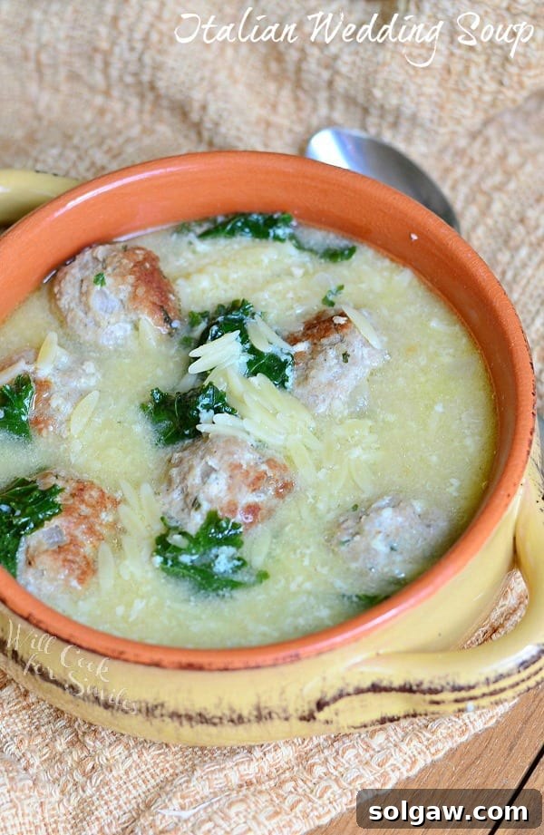 A hearty bowl of Italian Wedding Soup with succulent turkey meatballs, fresh kale, and tender orzo pasta, garnished with grated Parmesan cheese.