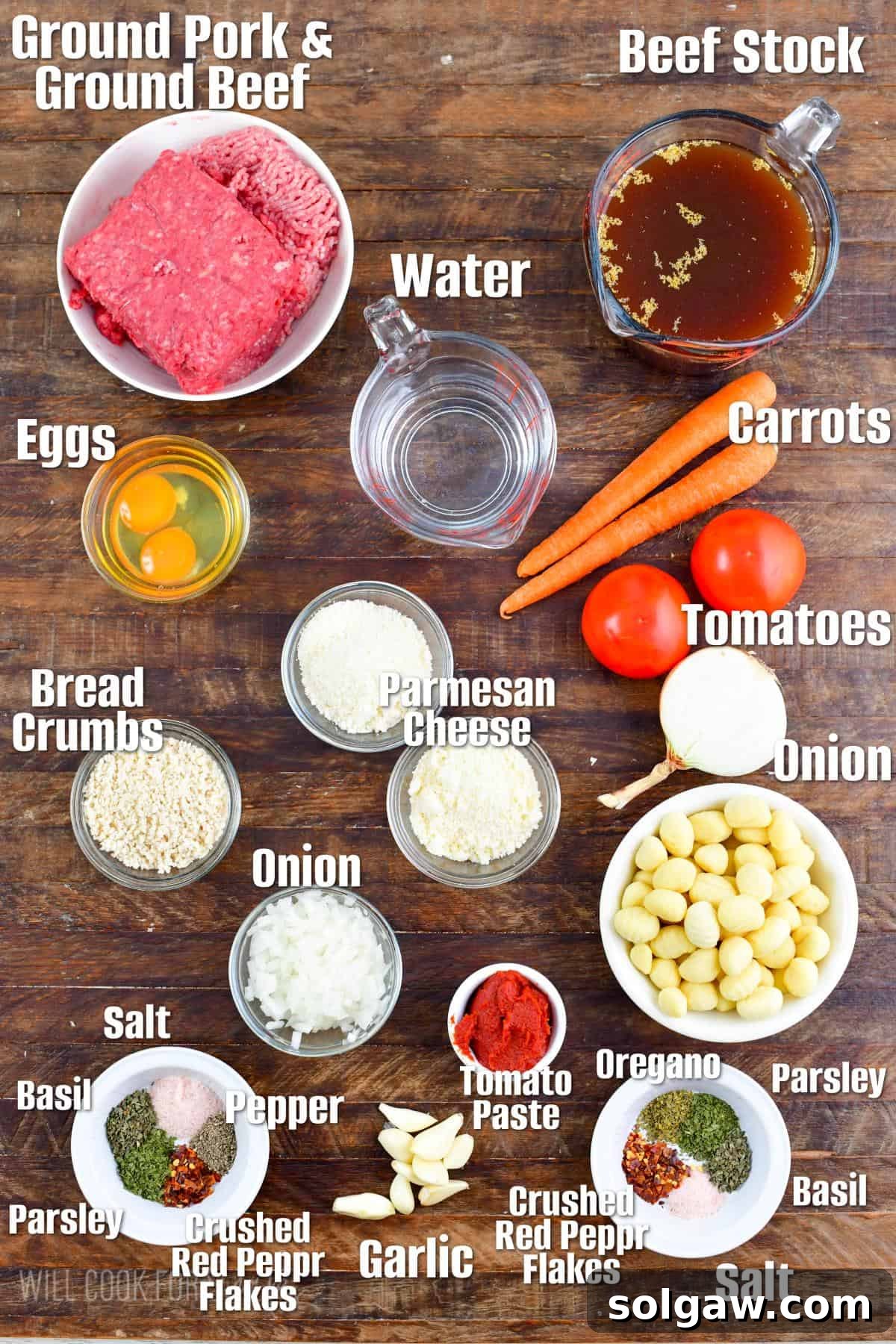 labeled ingredients to make Italian meatball and gnocchi soup on a wooden board.