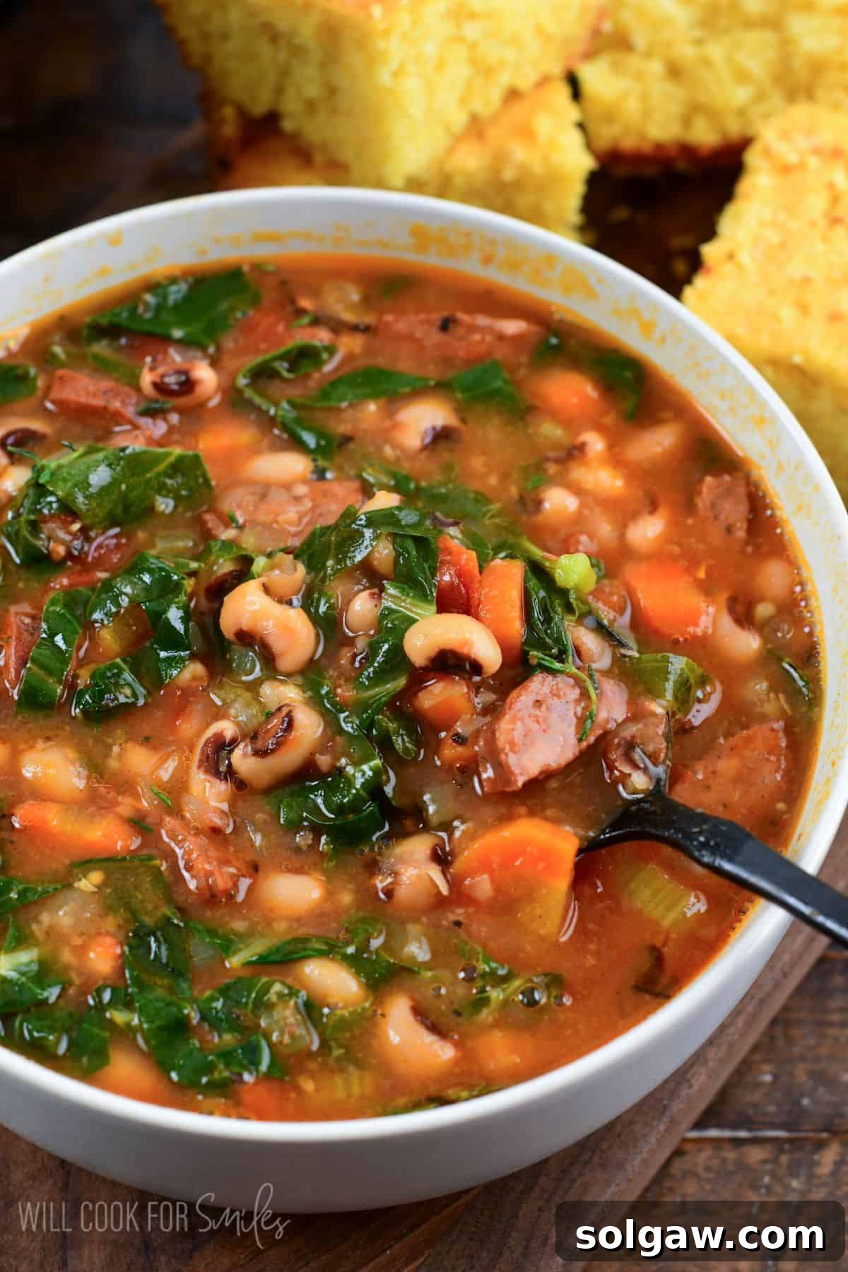 starting to spoon out some Southern black eye pea soup from a bowl next to fresh homemade buttermilk cornbread.