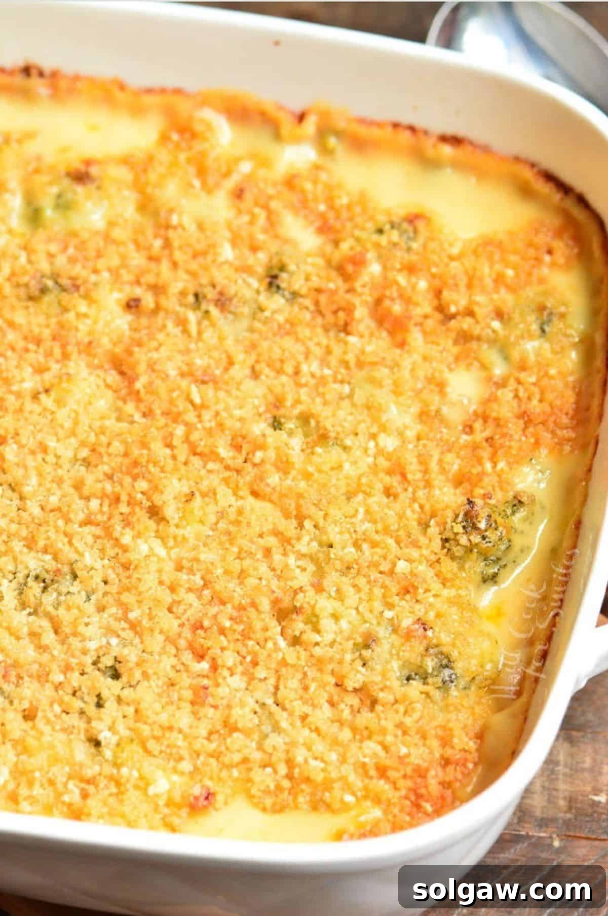 A freshly baked broccoli cheese casserole, golden brown and bubbling, presented in an elegant white baking dish.