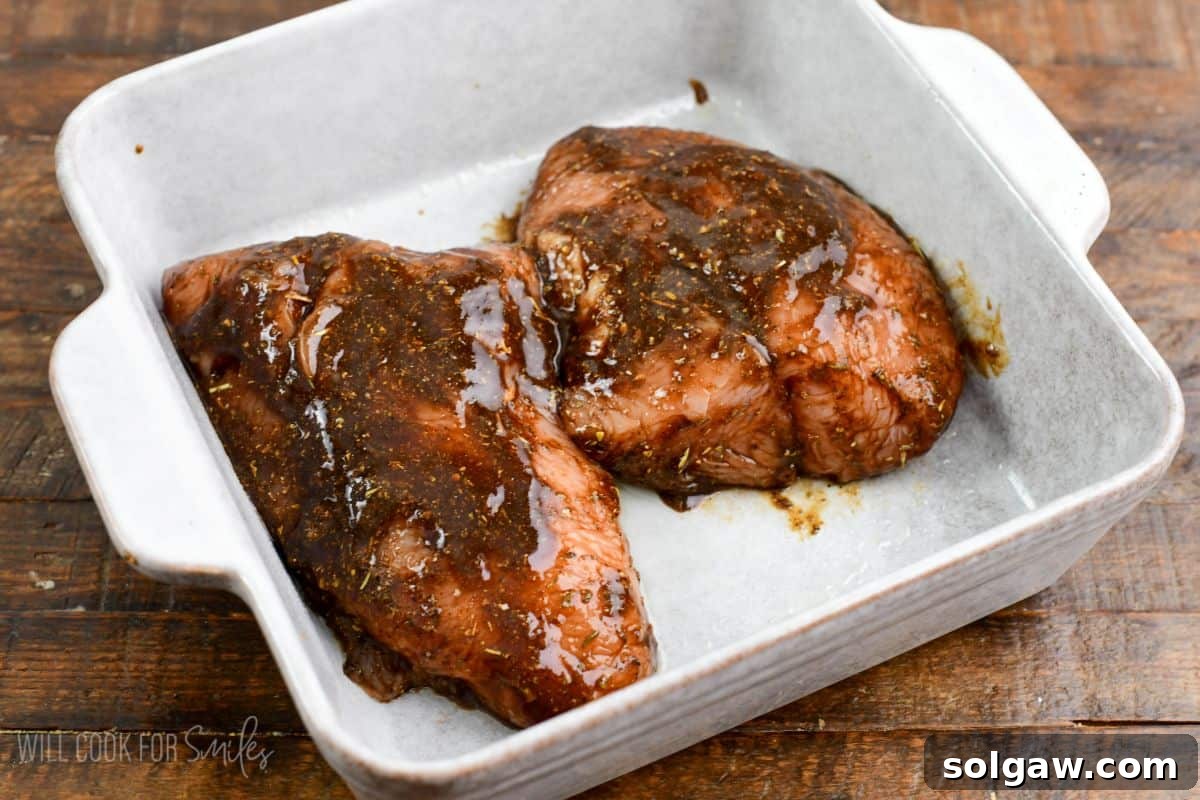 two turkey tenderloin breasts in a rich and flavorful balsamic marinade mixture in a baking dish.