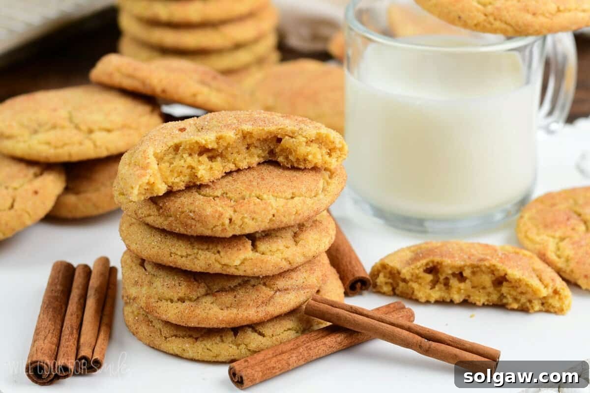 several soft and chewy snickerdoodle cookies stacked and some split in half next to glass of milk.