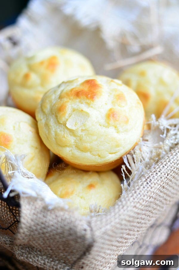 Lined basket with roasted garlic dinner muffins piled in, viewed from above.