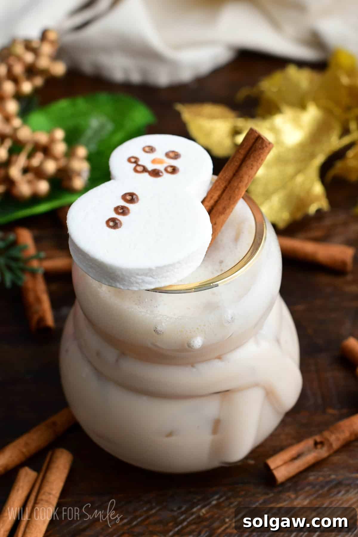 RumChata Cocktail in a glass with a cinnamon stick and a marshmallow snowman on top, exuding holiday cheer.