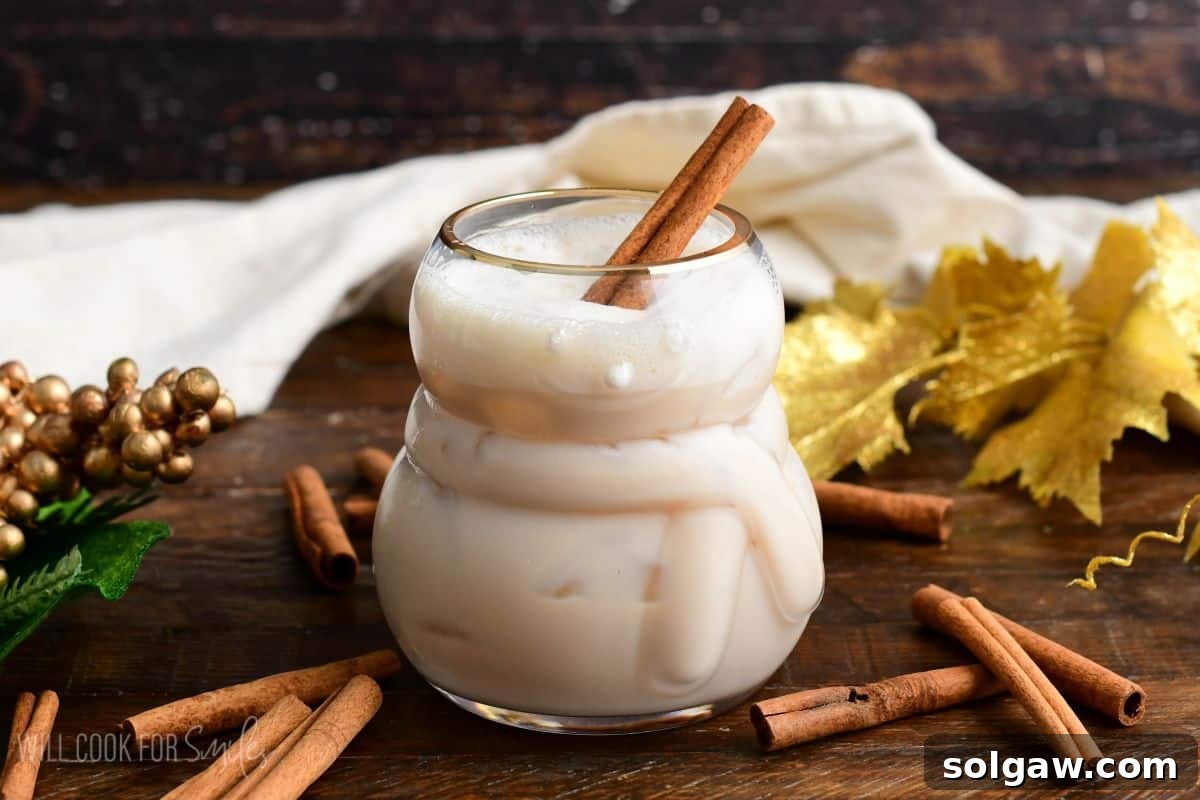 A RumChata cocktail in a whimsical snowman glass, complete with a cinnamon stick garnish, ready to be enjoyed.