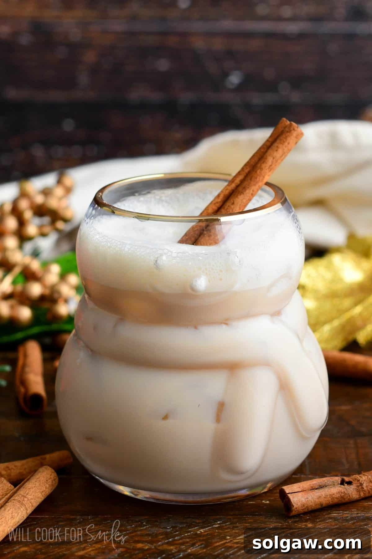 rumChata cocktail with a cinnamon stick in the glass on a wooden surface.