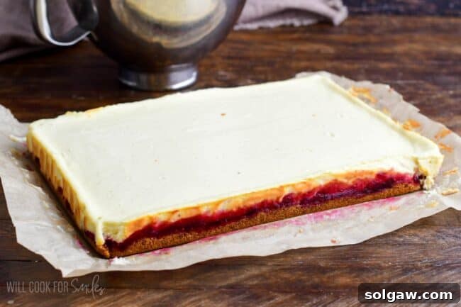 The fully baked and cooled Christmas Cheesecake bars, gently removed from the pan and resting on parchment paper on a wooden surface, ready for frosting.