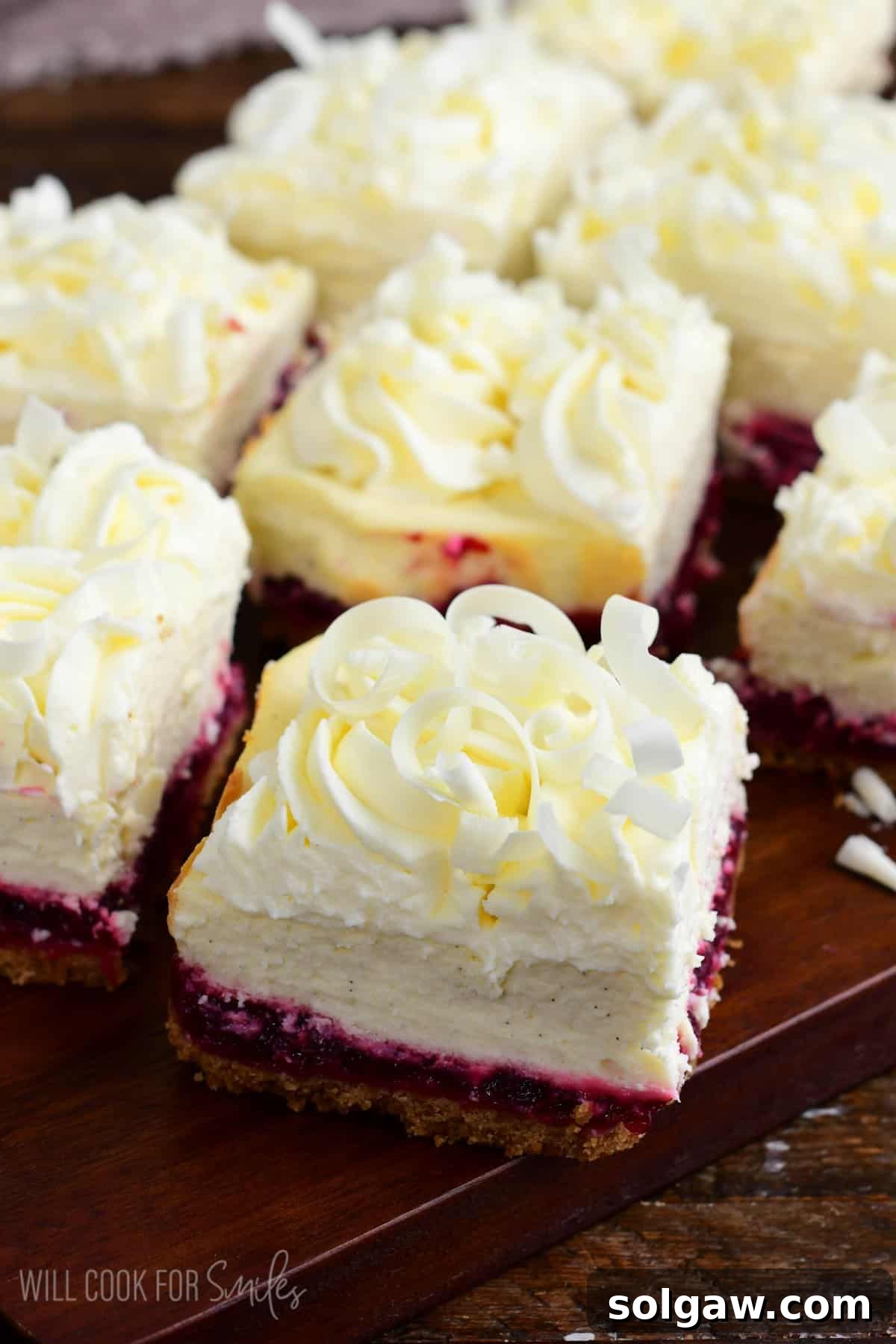 A festive spread of uncut Christmas cheesecake bars, beautifully adorned with delicate white chocolate shavings, arranged on a rustic wooden surface, ready for holiday enjoyment.