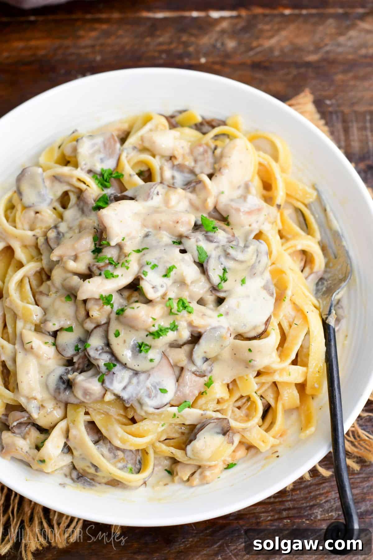 family recipe restaurant style creamy chicken stroganoff over pasta in a bowl.