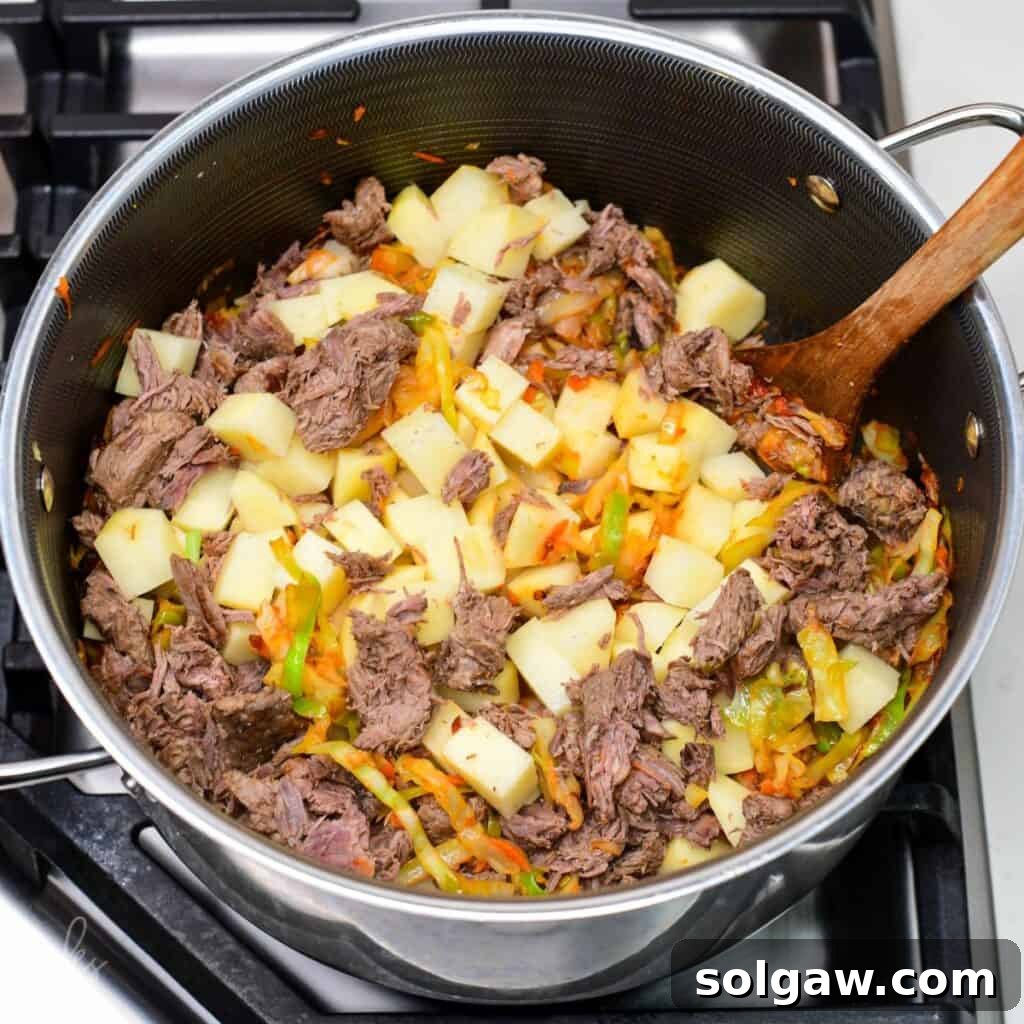 cubed potatoes and cooked tender beef added to the pot with cabbage and vegetables.
