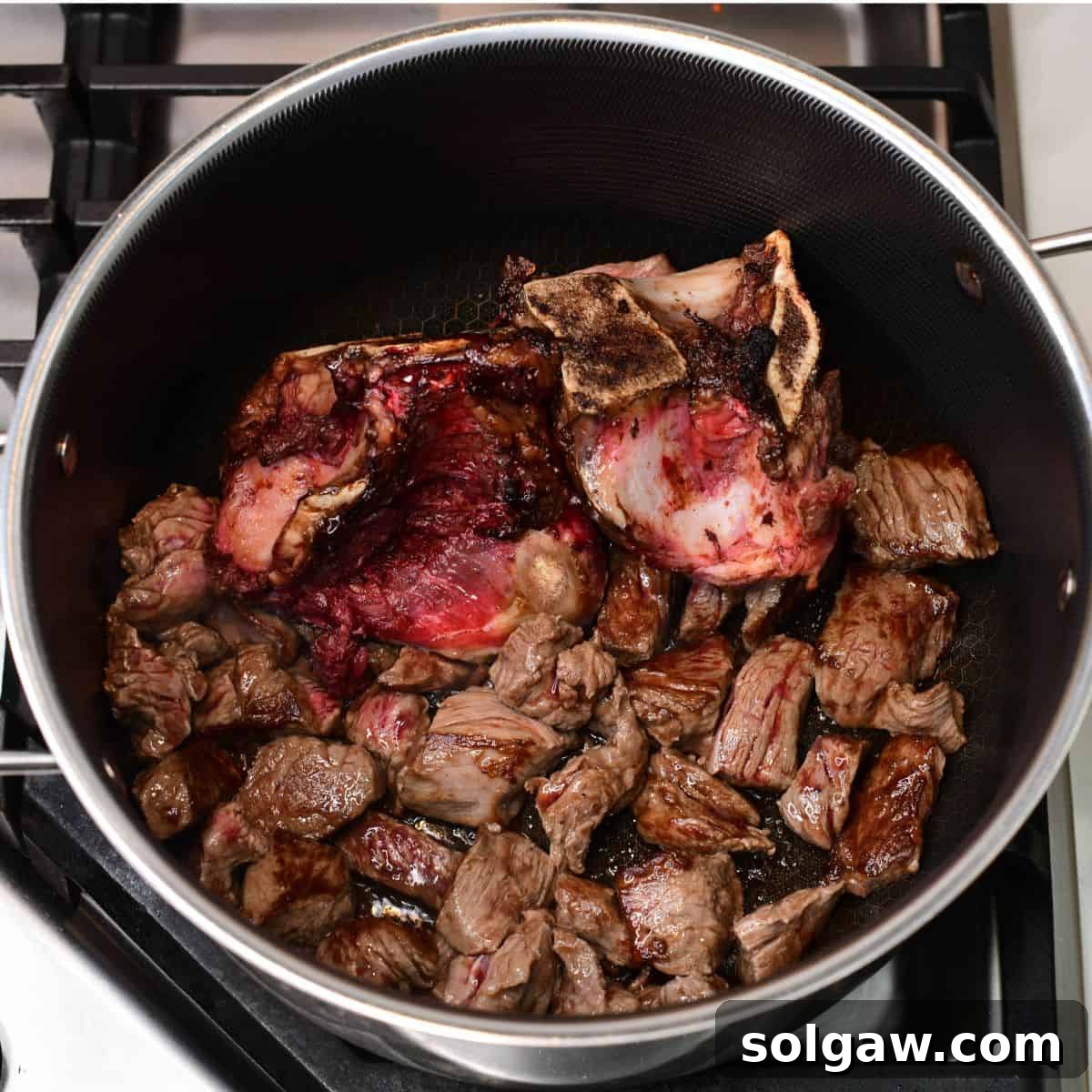 searing large beef bones and beef stew meat in the pot for the soup.