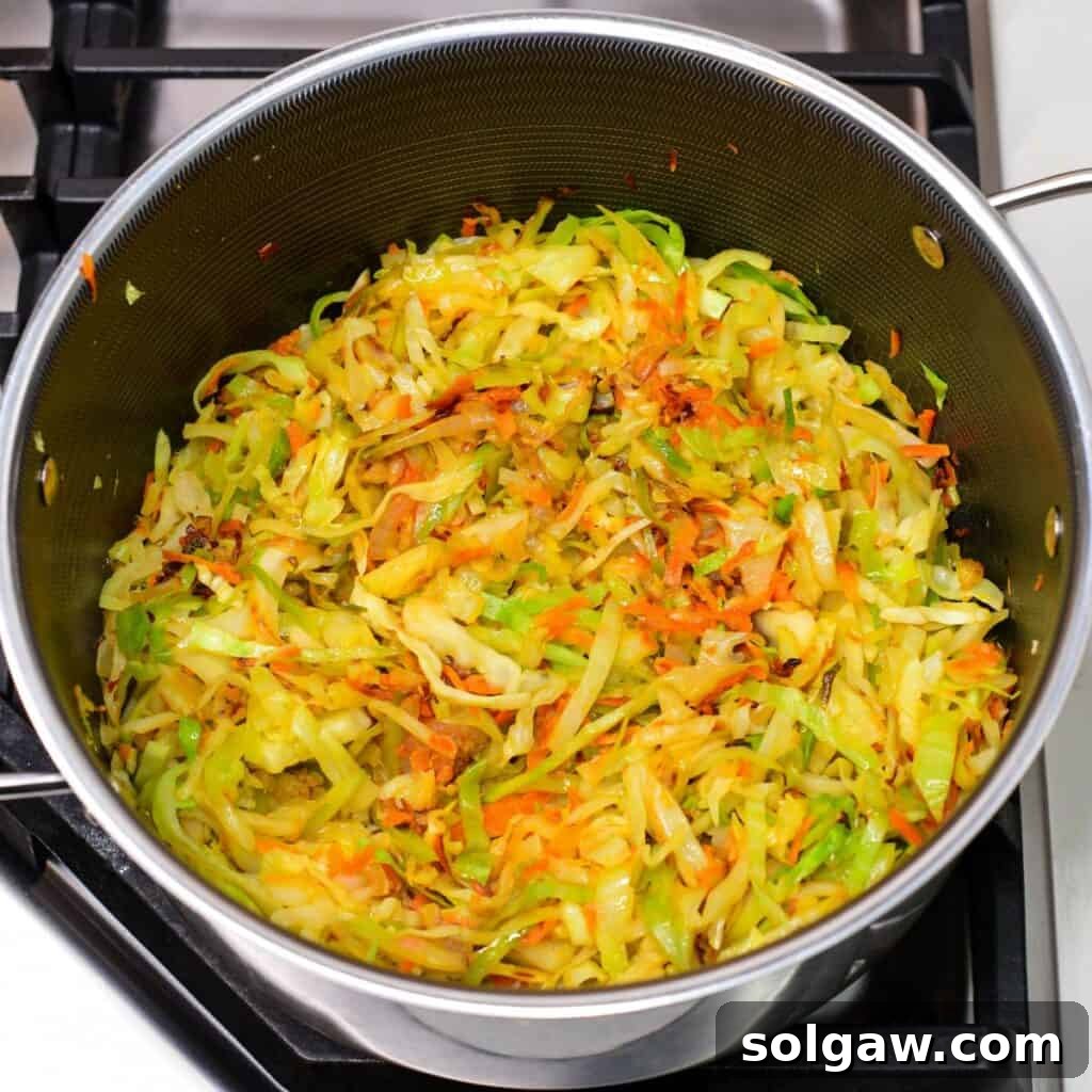 searing the finely sliced cabbage with onions and carrots in a pot.