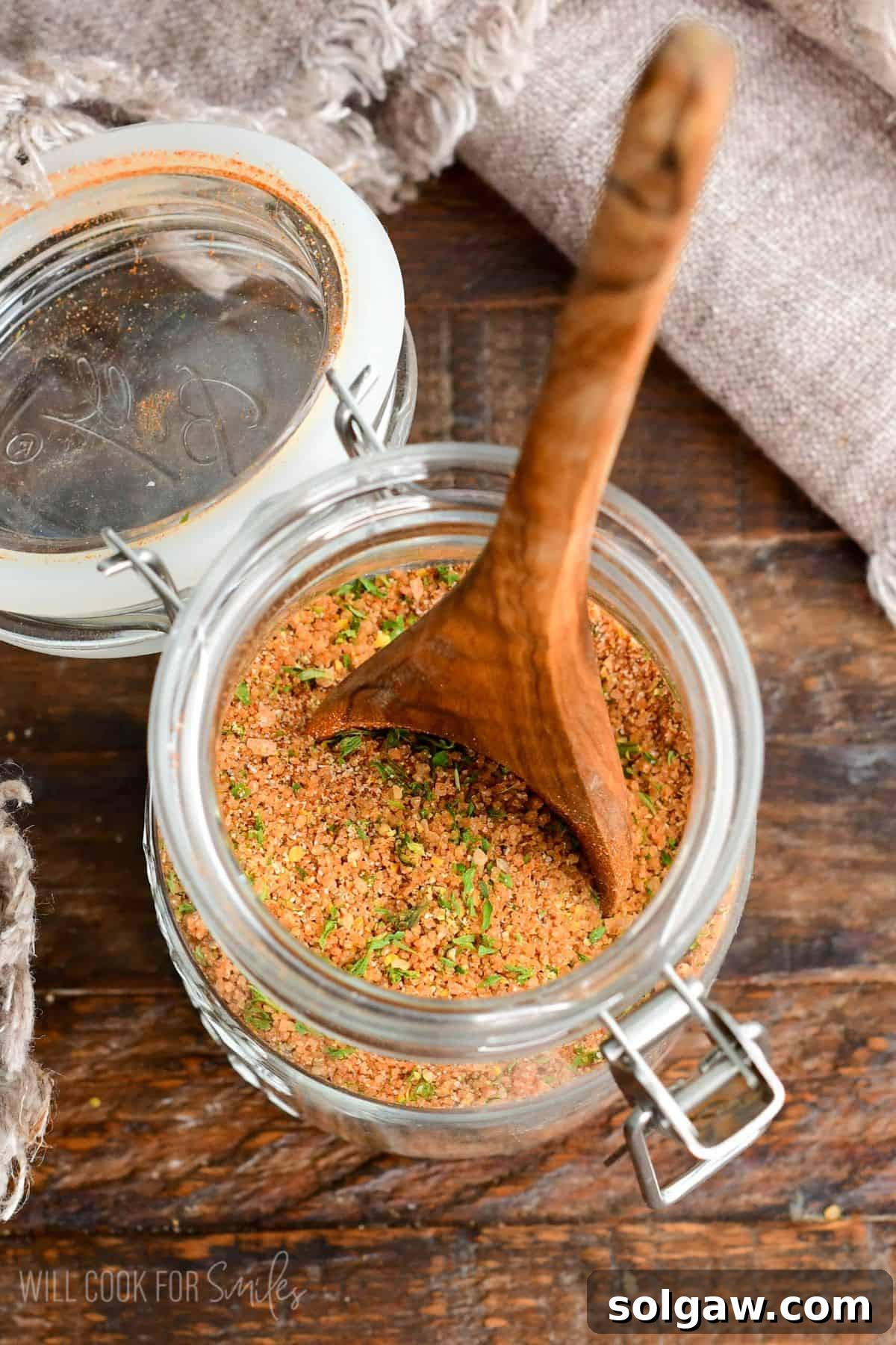 glass jar filled with pork rub seasoning and a wooden spoon in it.