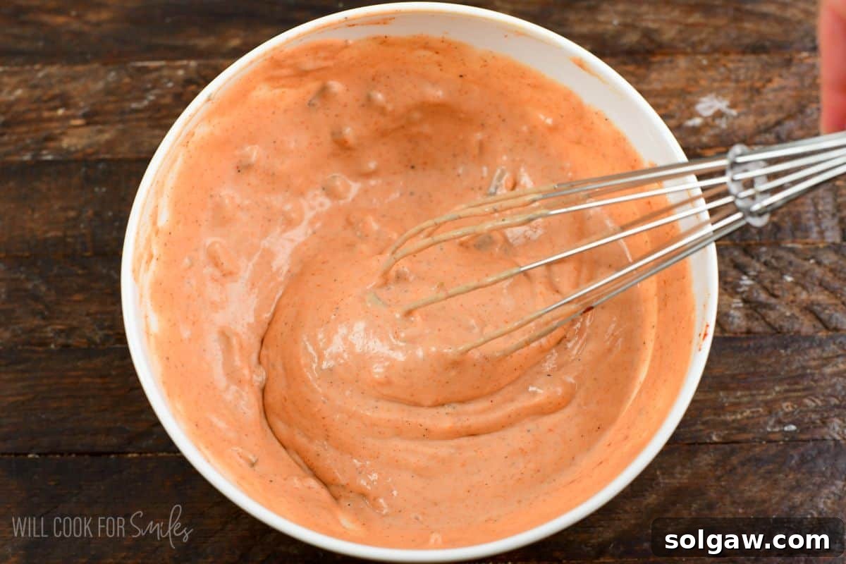burger sauce being mixed with a whisk in a bowl on a wood surface.