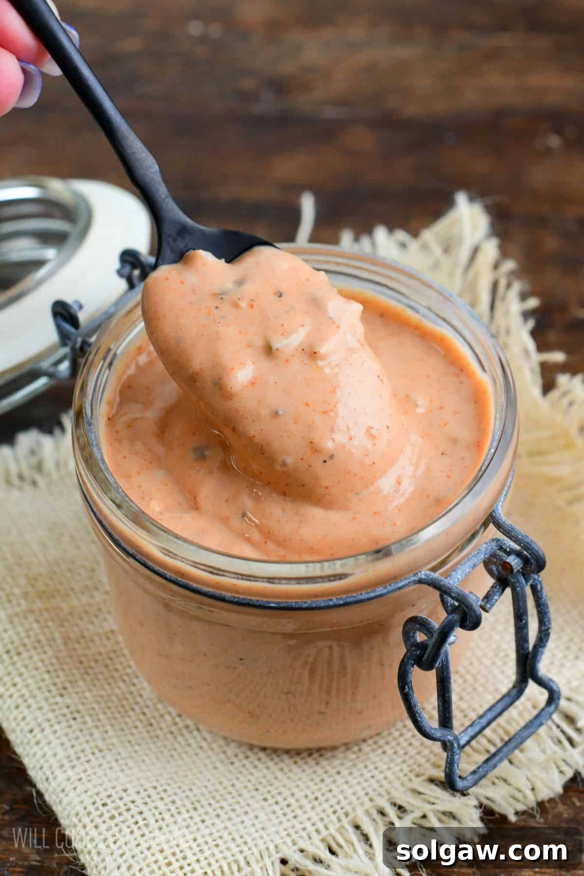 burger sauce in a jar with a spoon scooping some out.