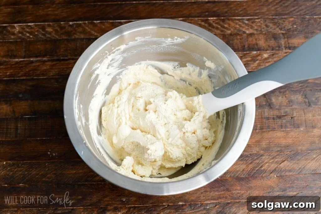 Creamy no-bake cheesecake filling, light and fluffy, mixed to perfection in a bowl with a spatula, ready for assembling the parfaits.