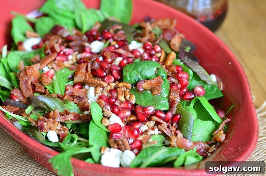A festive winter spinach salad, vibrant with pomegranate, goat cheese, and pecans, ideal for holiday meals