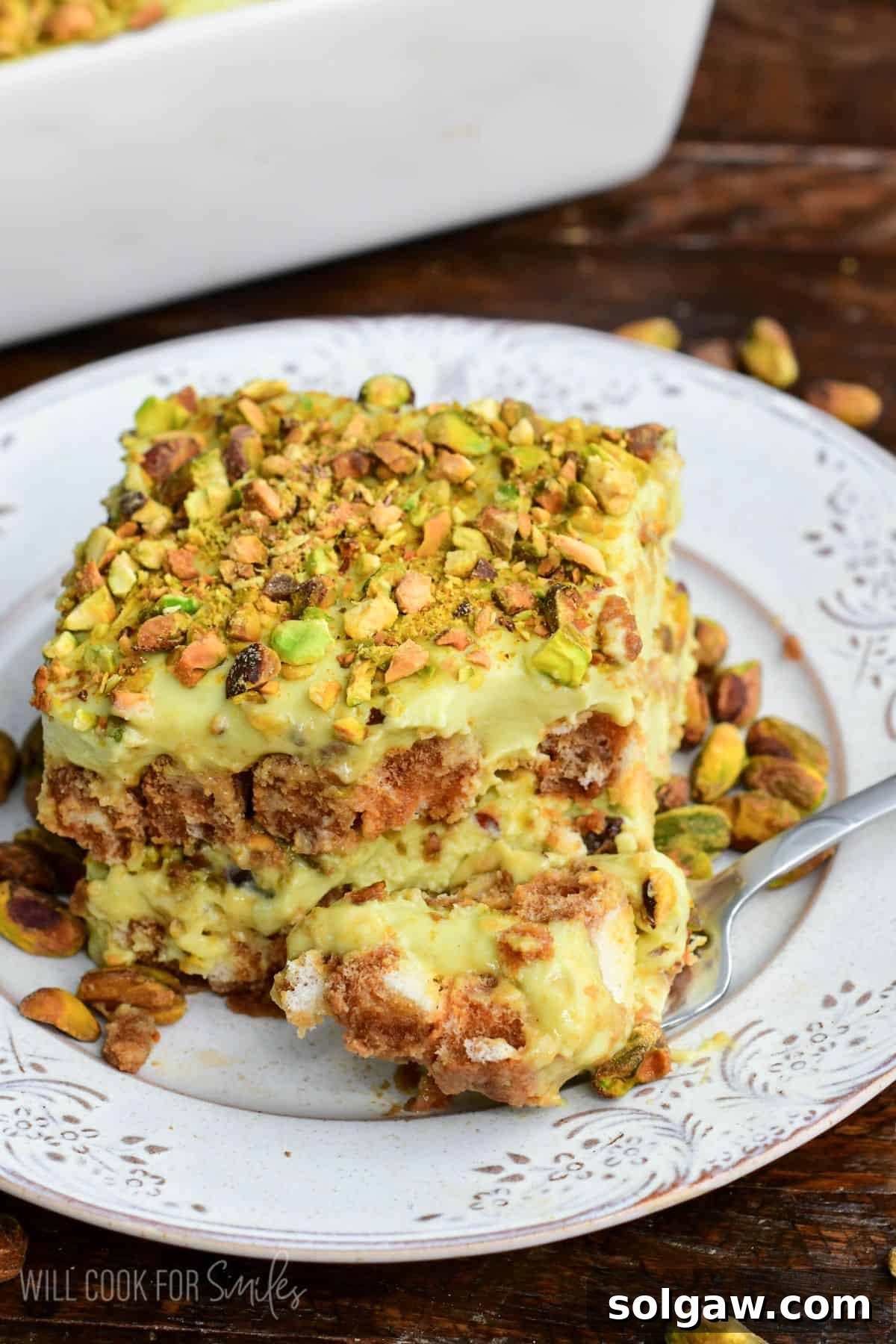 Velvet Pistachio Tiramisu 2 Fork with a bite of creamy pistachio tiramisu, showcasing luscious layers of pistachio mascarpone filling and coffee-soaked ladyfingers, finished with a crunchy sprinkle of chopped pistachios.