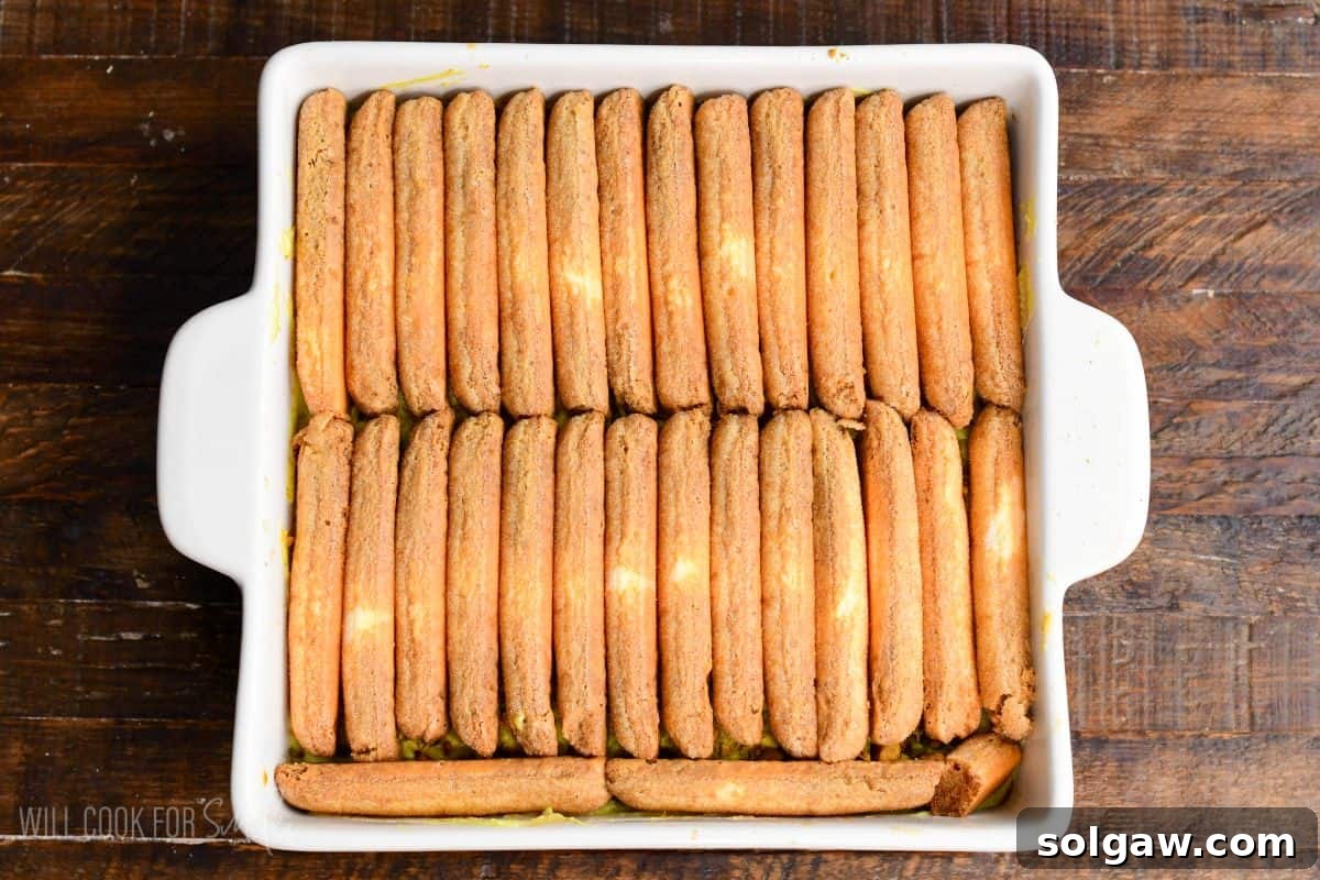 Velvet Pistachio Tiramisu 13 Second layer of ladyfingers neatly arranged in a white baking dish for pistachio tiramisu assembly.
