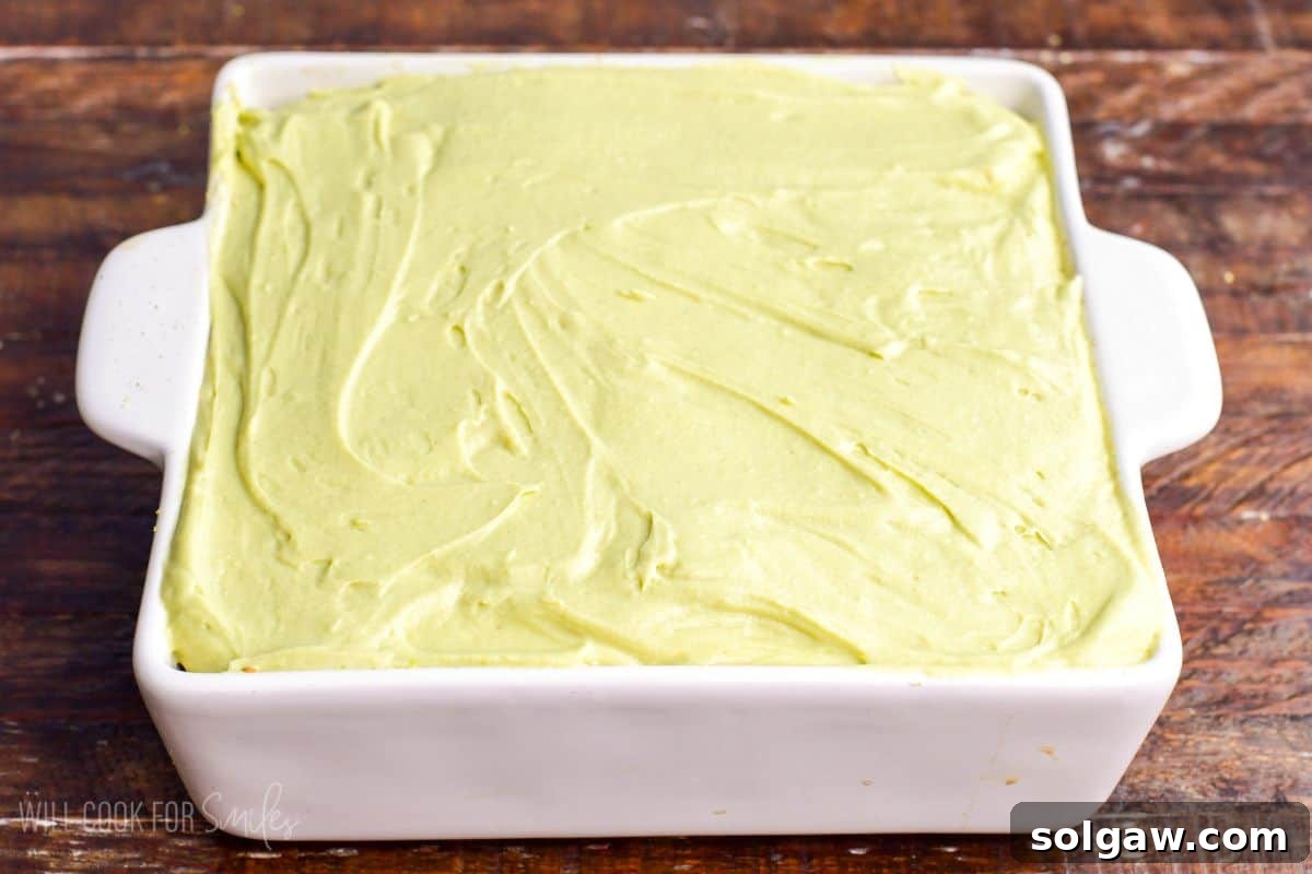 Velvet Pistachio Tiramisu 14 Final layer of creamy pistachio mascarpone mixture spread smoothly over tiramisu in a white baking dish before chilling.