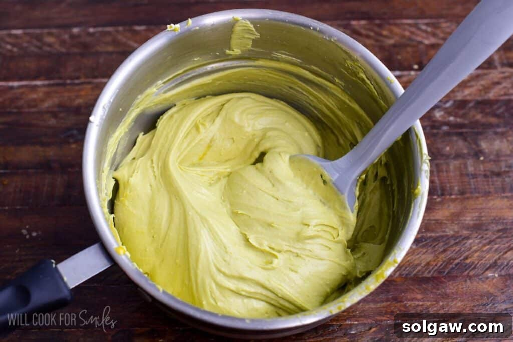 Velvet Pistachio Tiramisu 9 Mascarpone cheese folded into pistachio custard in a saucepan, creating a smooth, creamy pistachio mascarpone mixture.