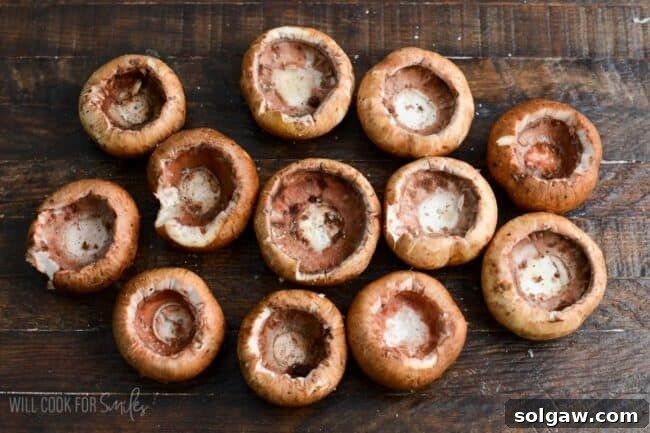 Hollowed out mushroom caps arranged on a wooden surface, prepared for stuffing.