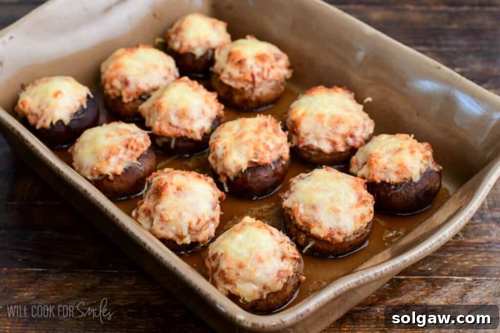 Baked Reuben stuffed mushrooms in a casserole dish with melted golden Swiss cheese on top.