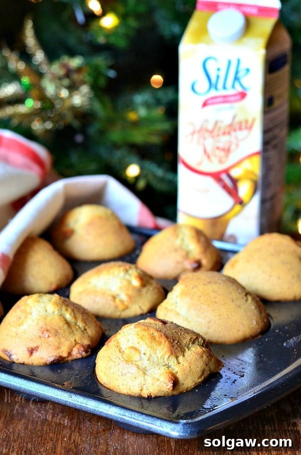 White Chocolate Chip Eggnog Muffins in a muffin tin with a carton of Silk Holiday Nog in the background