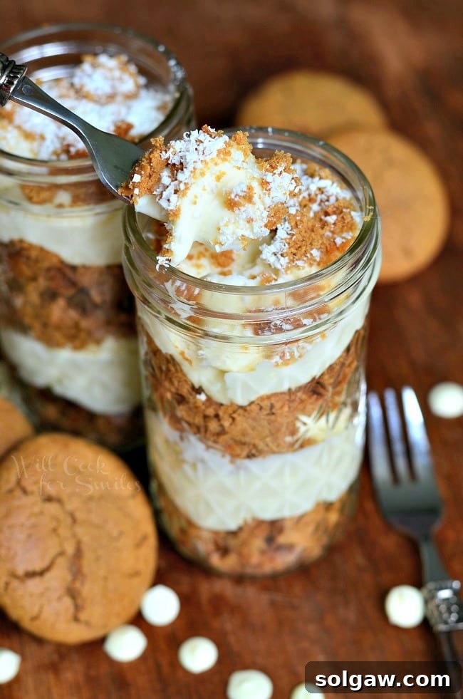A close-up of a Cheesecake Gingerbread Trifle in a mason jar, with a fork scooping out a bite.