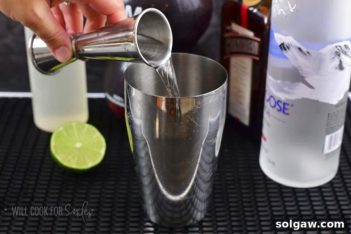 Vodka being carefully measured and poured into a cocktail shaker.