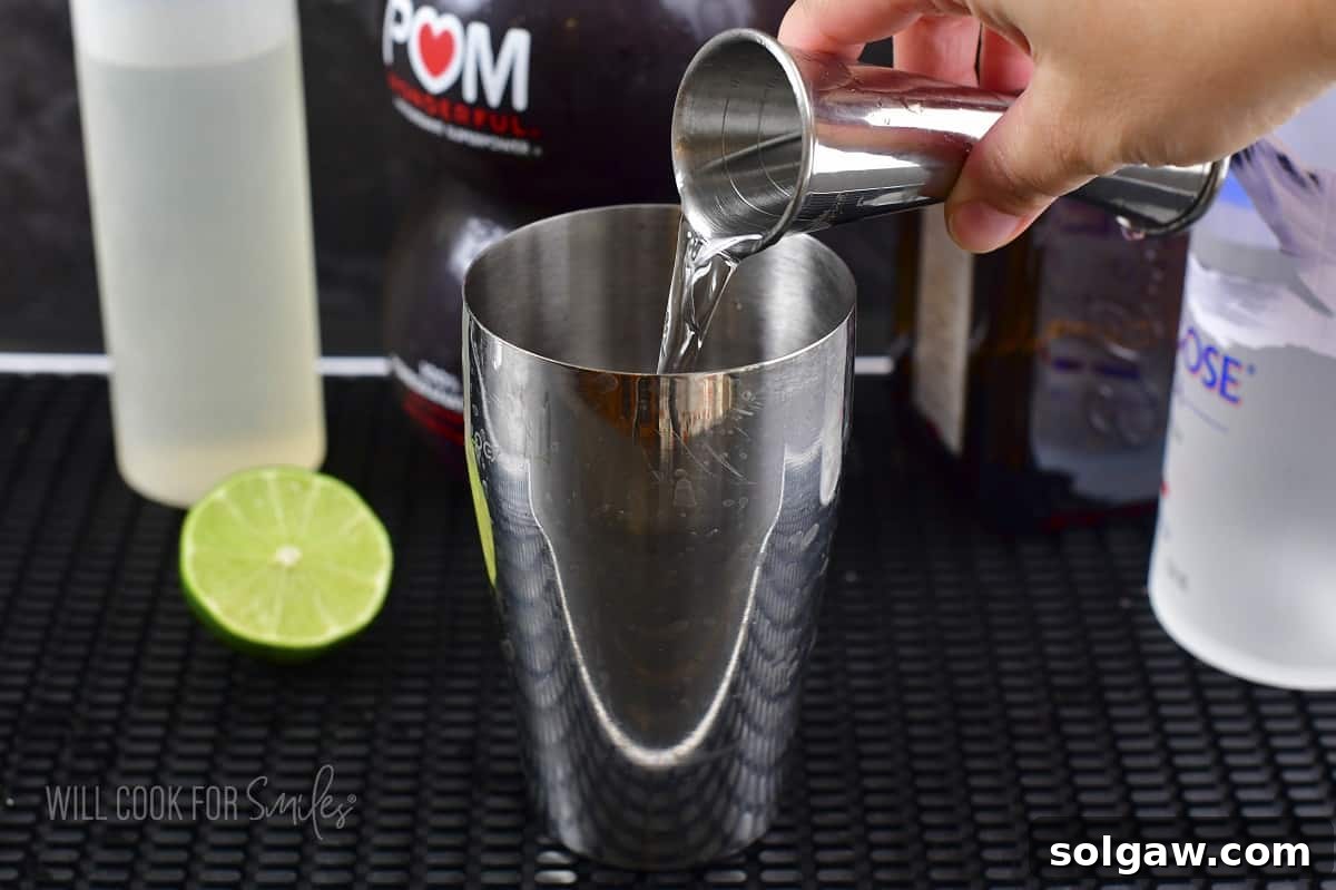 Orange liqueur (Cointreau) being added to the cocktail shaker with other ingredients.