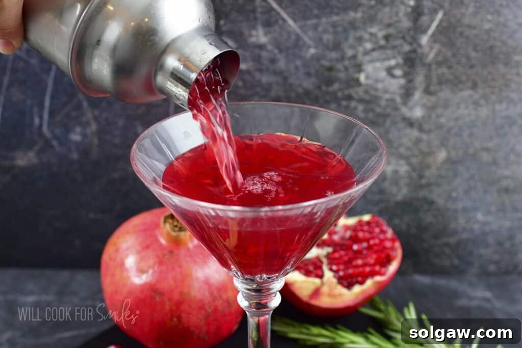 A freshly made Pomegranate Martini being poured into a chilled martini glass, ready for enjoyment.