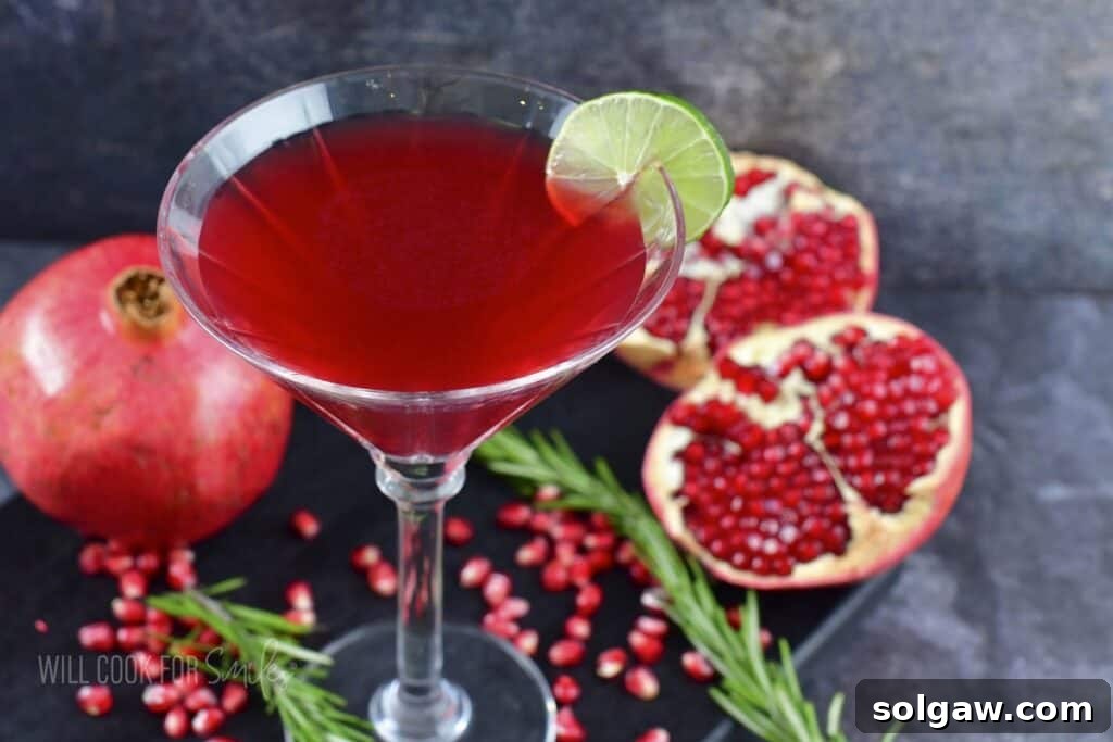 A close-up shot of a bright red Pomegranate Martini in a classic martini glass, highlighting its vibrant color and smooth texture.