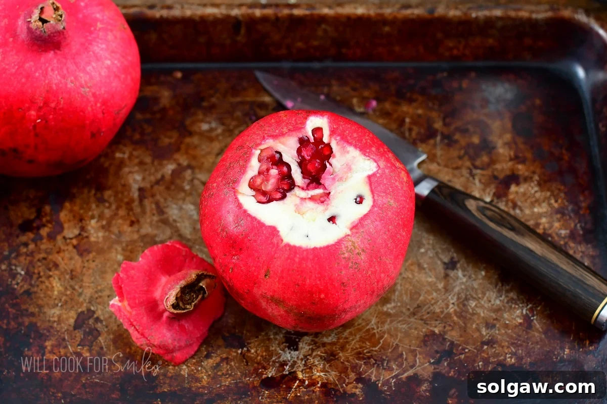 Pomegranate with its top precisely cut off, revealing the internal structure and top layer of seeds.
