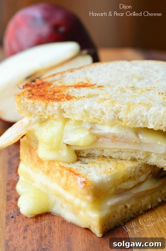 Dijon Havarti & Pear Grilled Cheese: A gourmet sandwich featuring creamy Havarti, honey-seared pear, and a hint of Dijon mustard, served on crispy sourdough bread.