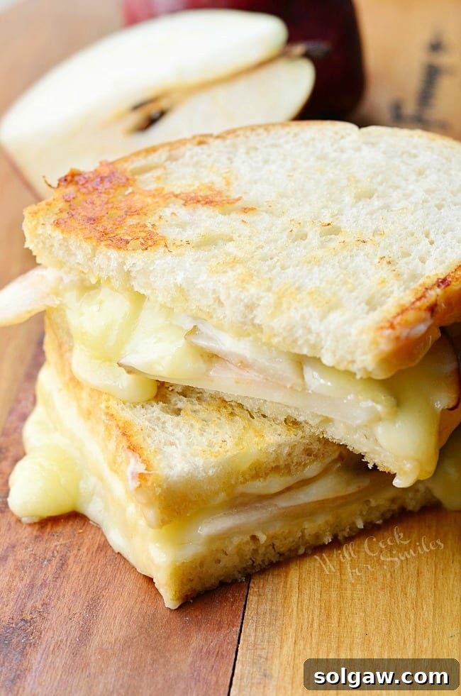A delicious Dijon Havarti & Pear Grilled Cheese sandwich, cut in half, displayed with its golden-brown crust and melted cheesy interior.