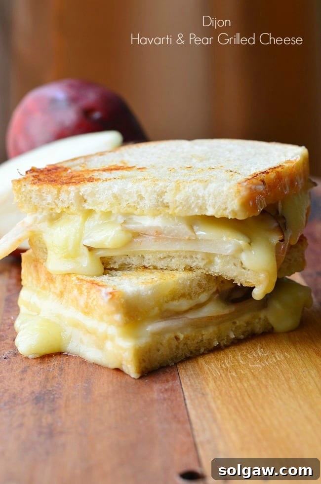 An appetizing image of a Dijon Havarti & Pear Grilled Cheese sandwich, golden and inviting, ready to be enjoyed.