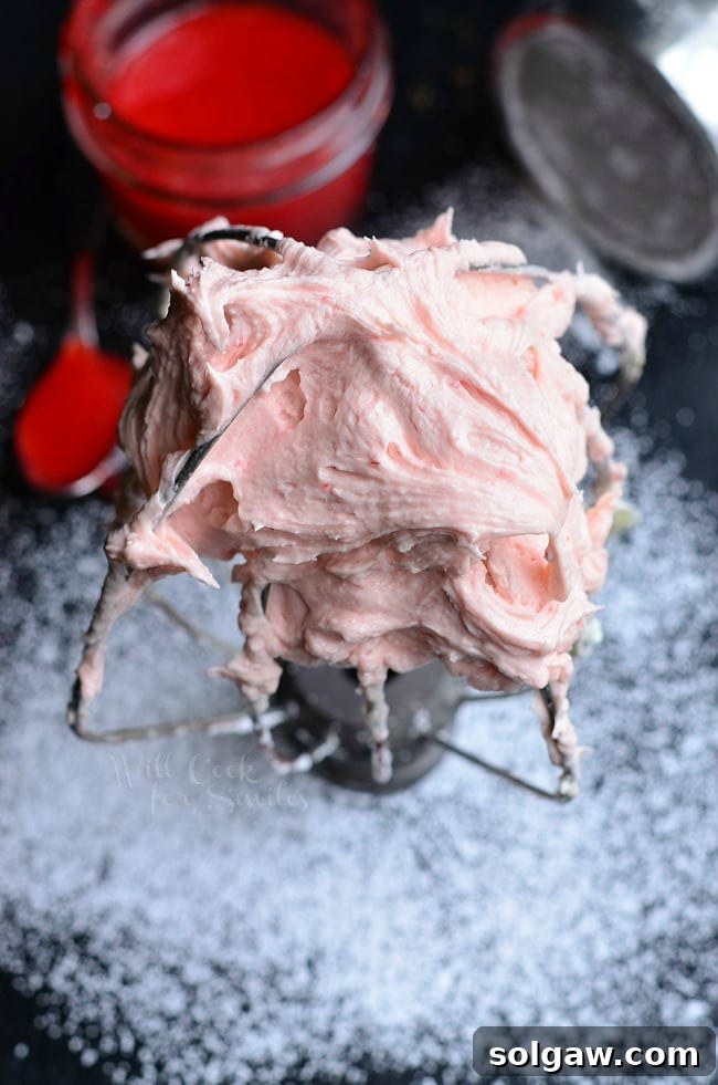 Freshly whipped Strawberry Buttercream Frosting in a stand mixer, showcasing its light and airy texture.