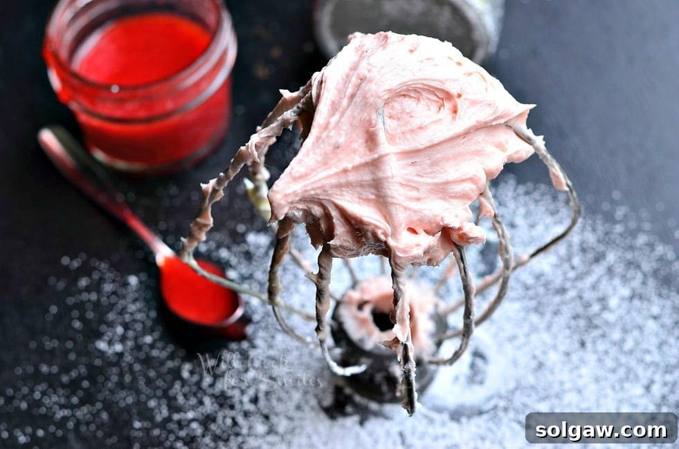Ingredients for Strawberry Buttercream Frosting: a bowl of whipped butter and a jar of homemade strawberry sauce.