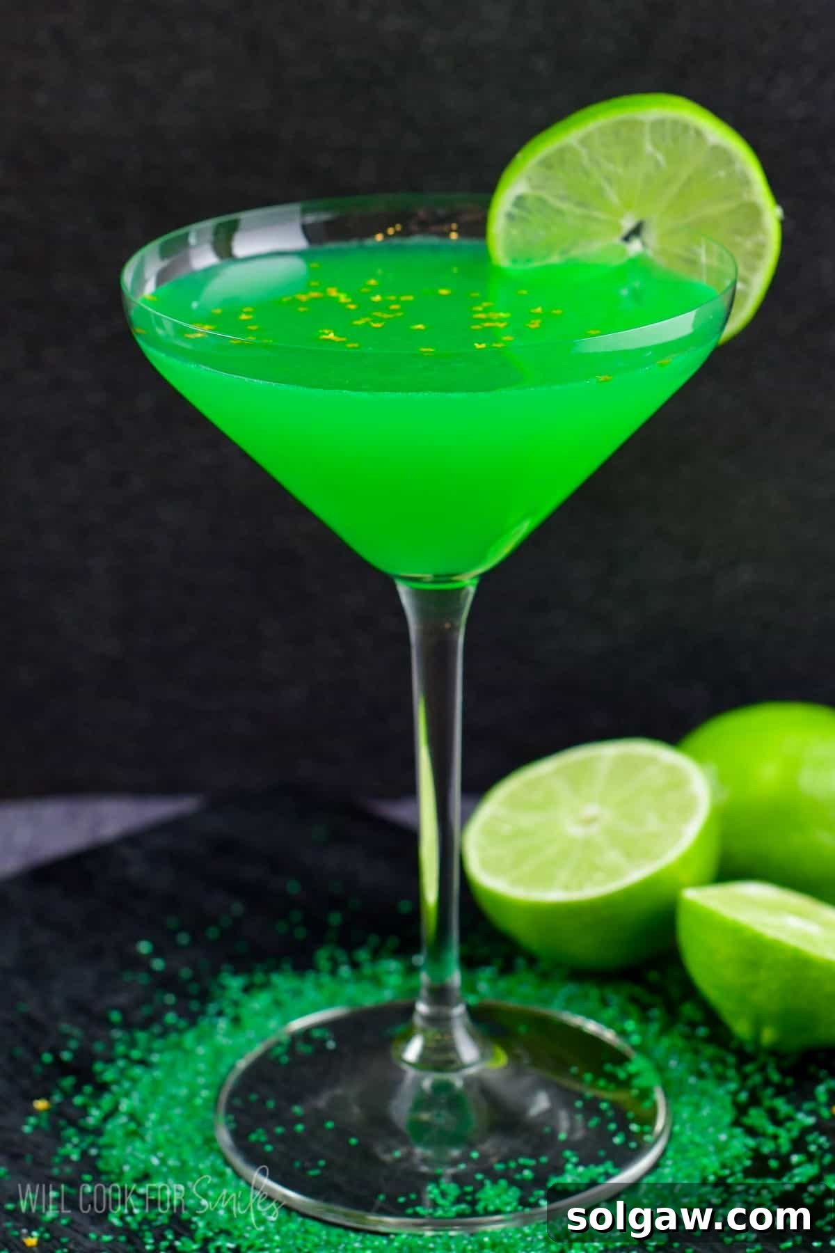 A perfectly prepared lime martini in a glass, featuring a lime wedge artfully placed on the side and green sprinkles at the elegant base of the glass.
