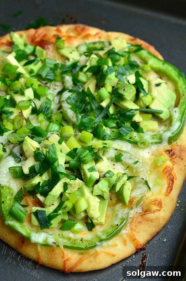 Top-down view of Green Naan Pizza, highlighting the fresh avocado, green peppers, and scallions.