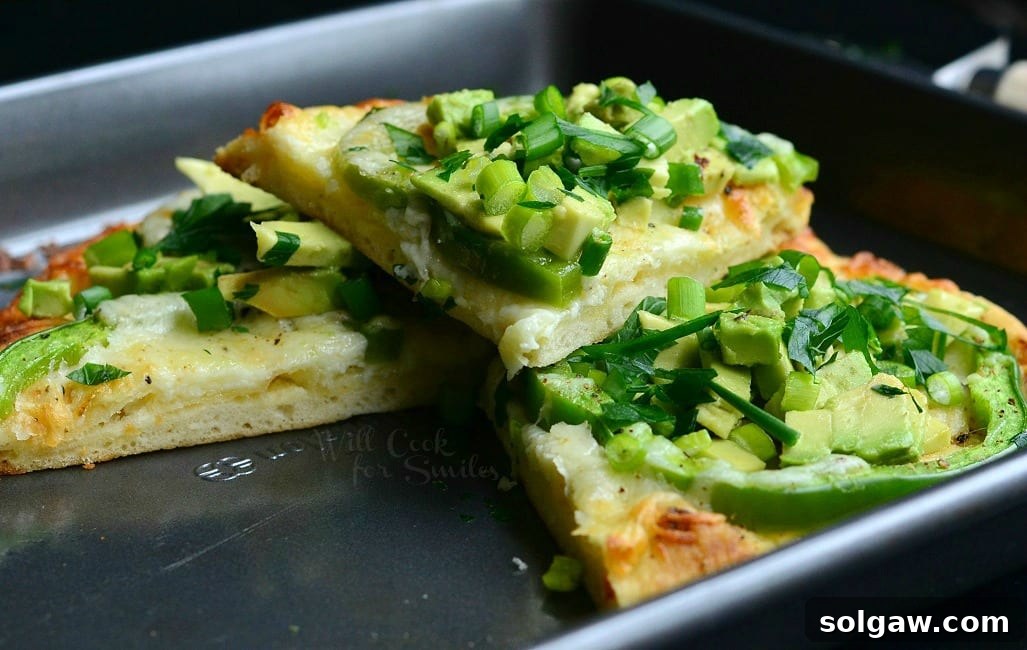 Green Naan Pizza with avocado, green peppers, and green onions on top in a baking pan, ready to be served.