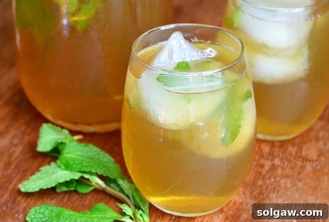 A glass of Honey Mint Green Iced Tea with ice and fresh mint leaves